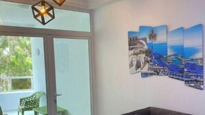 Sala de estar com um sofá escuro, almofadas xadrez e luminária no teto.