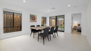 Un comedor moderno con una gran mesa y sillas, ventanas amplias y vistas al exterior.