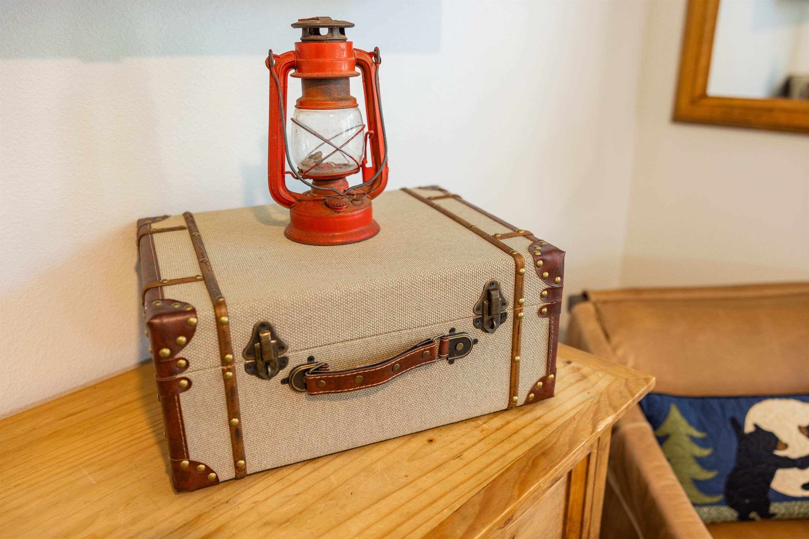 Une vieille valise sur laquelle est posée une lanterne, le tout placé sur une table en bois.