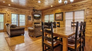 A wooden cabin interior with a dining table, chairs, sofas, and a ceiling fan. - Gatlinburg Heights, Hot Tub, Game Room, Theater Room, FREE Attraction tickets (Gatlinburg)