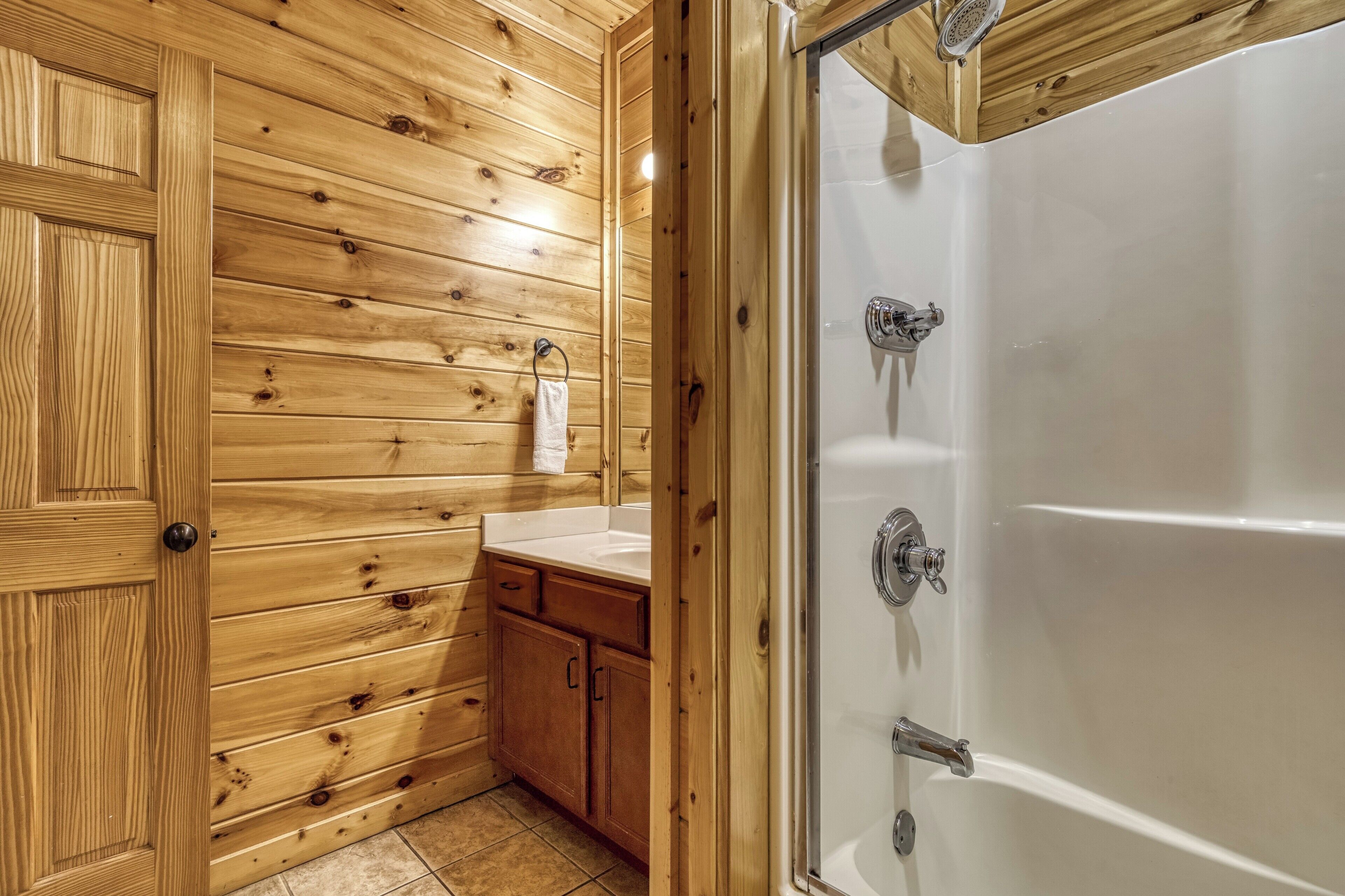 A wooden-paneled bathroom with a bathtub and a sink.