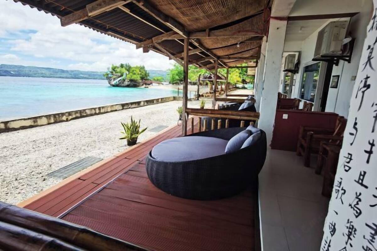 Un espacio de estar al aire libre techado con vistas a una playa y al océano.
