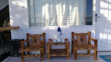 A room with two wooden chairs, a small table, and a window with curtains.