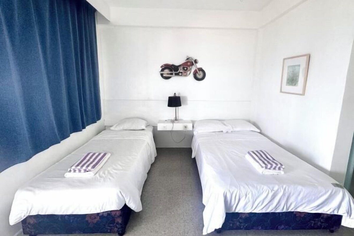 A twin room with two beds, a motorcycle on the wall, a lamp, and a framed picture.