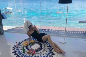 A person relaxing on a patterned mat by a window overlooking a body of water. - Jelly Sea Resort (Siquijor Island)