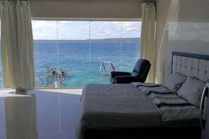 Ein Schlafzimmer mit Bett, Stuhl und Meerblick.