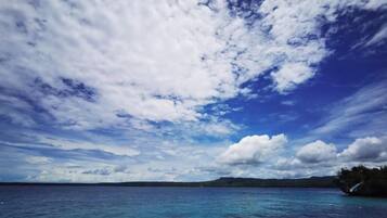 Vista de un cuerpo de agua con una masa de tierra distante y un cielo parcialmente nublado.