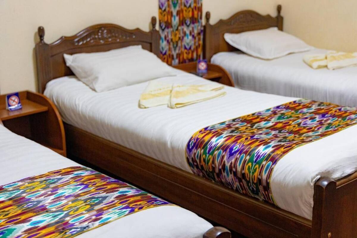 Two single beds with wooden headboards, white bedding, and colorful blankets.