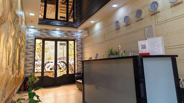 A reception area with a modern design, featuring a reception desk, a wall clock, and a decorative glass door. - Shakh Sultan Hotel (Tashkent)