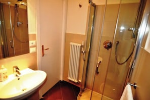 A bathroom with a glass-enclosed shower, a white sink, and a visible towel rack.