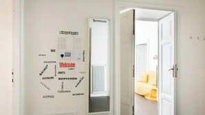 A hallway with a welcome sign and a door leading to a room with a yellow bed. - Spacious and Bright Apartment in the Heart of Rome (Roma)