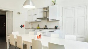 A modern kitchen with white cabinetry, a central island with chairs, and a pendant light. - Spacious and Bright Apartment in the Heart of Rome (Roma)