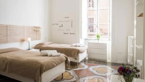 A hotel room with two beds, a window with blinds, a wall with text, and a radiator. - Spacious and Bright Apartment in the Heart of Rome (Roma)