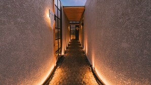 Ein schmaler Korridor mit Steinböden und -wänden, beleuchtet durch warmes Licht.