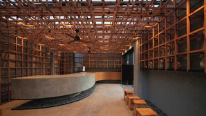 Ein modernes Interieur mit einer gewölbten Theke, Holzmöbeln und einer gitterartigen Deckenkonstruktion.