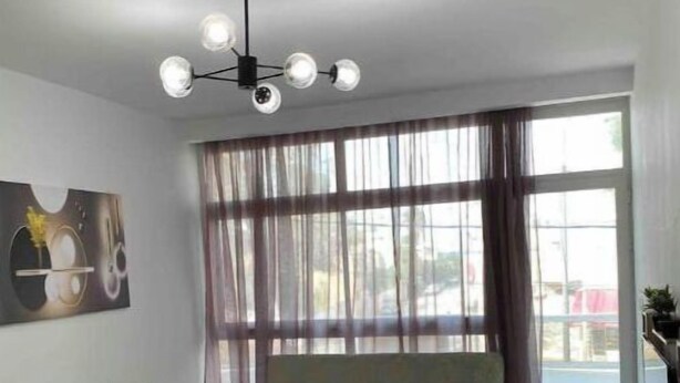Een moderne woonkamer met een bank, een eettafel en een kroonluchter.