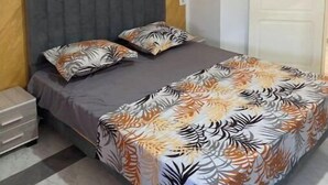 Een slaapkamer met een bed, nachtkastje, kast en deur.