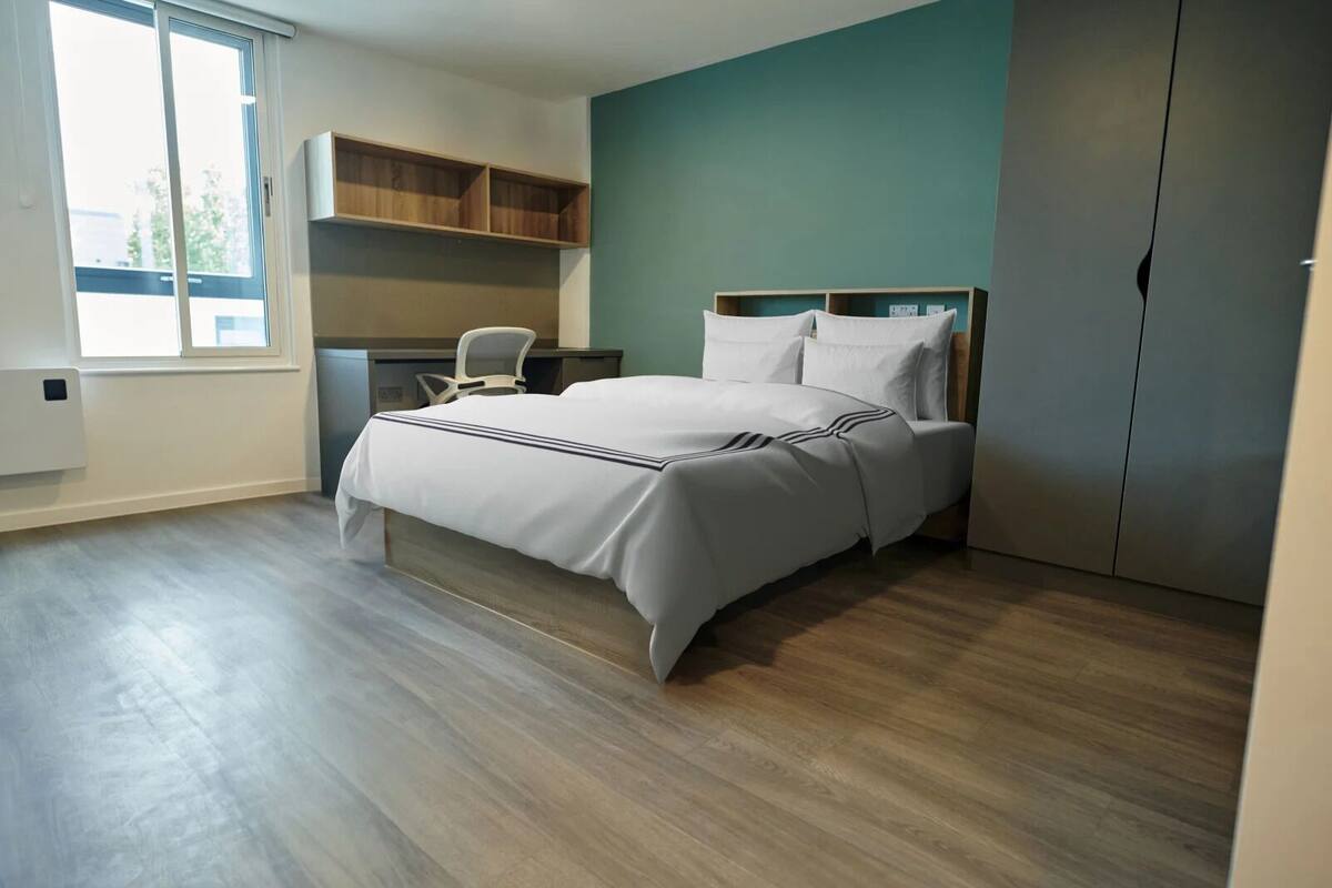 Quarto com cama, escrivaninha e guarda-roupa.