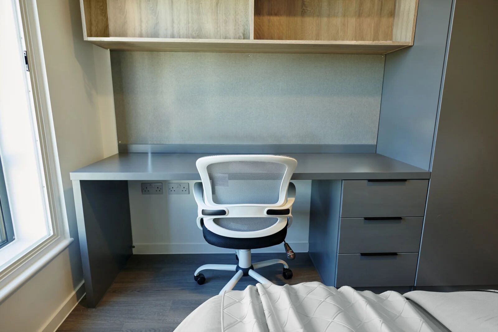 A modern office space with a desk, chair, and built-in shelving.
