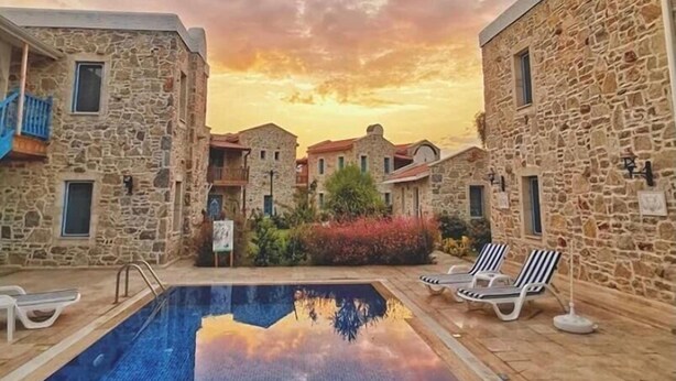 A stone building with a swimming pool and lounge chairs. - La petra boutique hotel (Datça)