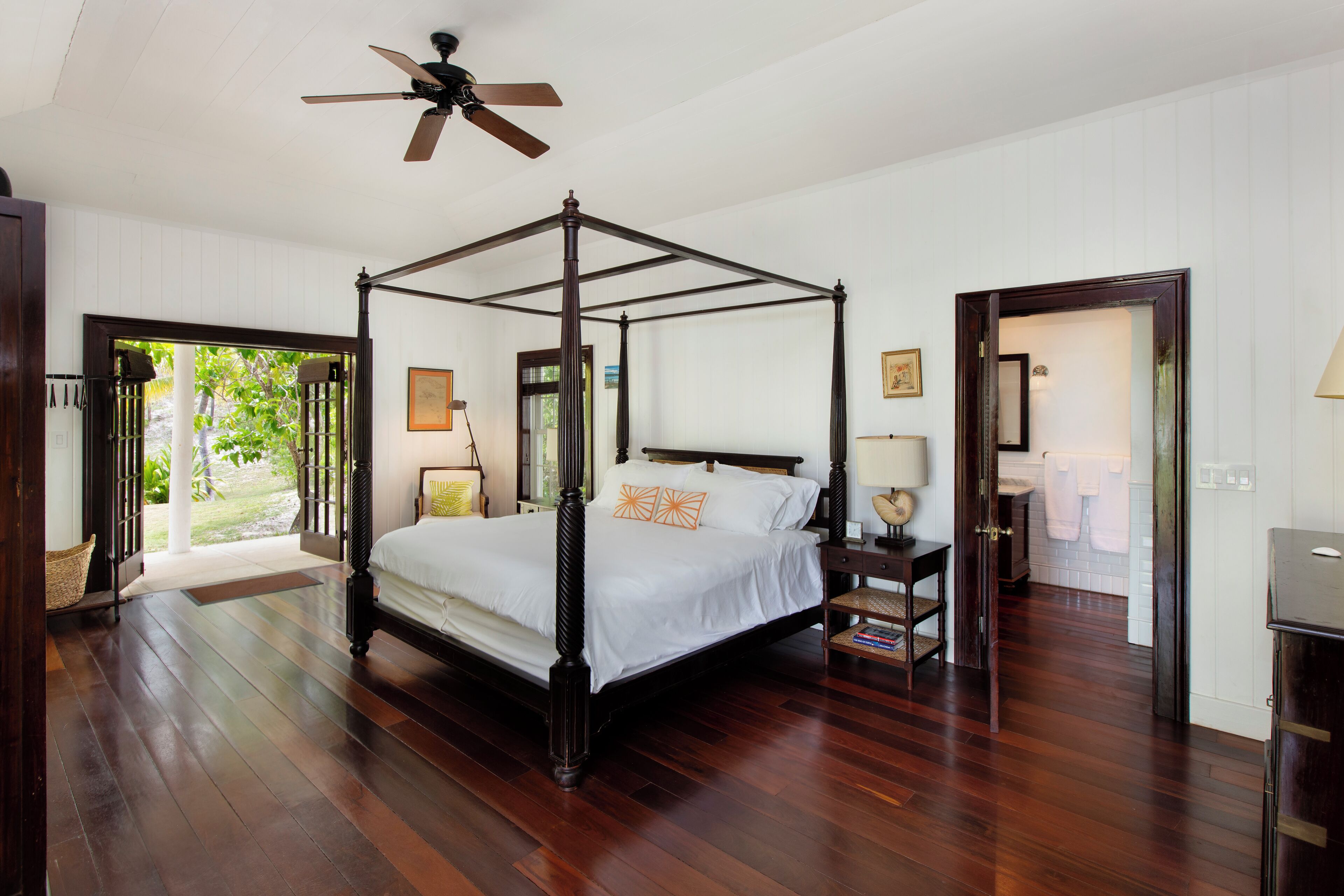 Un lit à baldaquin avec un ventilateur de plafond, un plancher en bois et une vue sur l’extérieur.