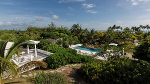 Un resort con piscina, un pabellón blanco y abundante vegetación.