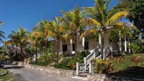 Un resort con un edificio blanco, palmeras y un muro de piedra.