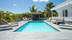 A wooden deck with a swimming pool, lounge chairs, a gazebo, and palm trees. - Caribbean Cliffside: Private Waterfront Retreat (North Palmetto Point)