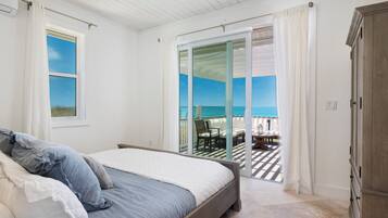 A bedroom with a bed, a wardrobe, and a view of a balcony with outdoor furniture.