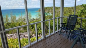 A wooden deck with a view of the ocean and lush greenery. - Island Oasis: Luxury Villa With Private Pool And Beach Access (Savannah Sound)