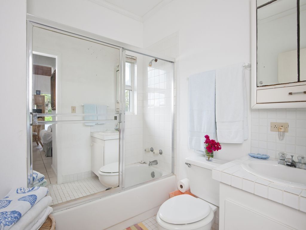 Une salle de bain moderne avec une douche à l’italienne en verre, des toilettes blanches et une baignoire.