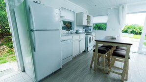 Een moderne keuken met witte kastjes, een inbouwoven en een eethoek met houten krukken.