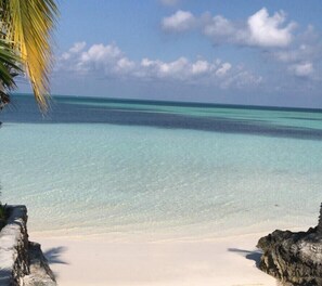 A beach with clear turquoise water, white sand, and rocky outcrops. - Caribbean Haven: Secluded Retreat With Stunning Ocean Views (Russell Island)