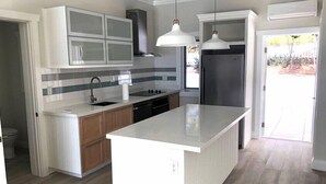 A modern kitchen with a central island, a double sink, and a built-in oven. - Oceanfront Haven: Elegant Estate With Private Deck (James Cistern)