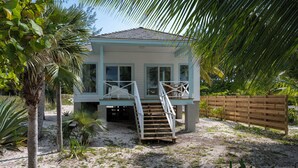 Ein Strandhaus mit einer kleinen Terrasse und einer Treppe zu einem überdachten Bereich.