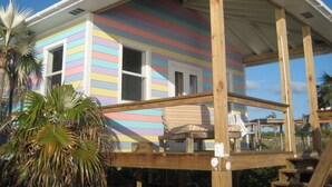 Une maison aux couleurs vives, dotée d’une terrasse en bois et d’un porche abrité.