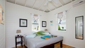 Une chambre à coucher avec un lit, une table de chevet, une lampe et une grande fenêtre avec des rideaux.