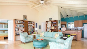 A cozy living room with a sofa, two armchairs, a coffee table, and a bookshelf filled with books.