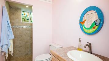 Une salle de bain équipée de toilettes, d’un lavabo et d’un miroir décoratif orné d’un motif de sirène.