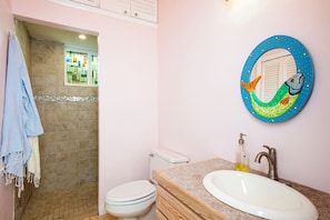 A bathroom with a toilet, sink, and a decorative mirror with a mermaid design. - Island Paradise: Secluded Beachfront Retreat With Pool (Rainbow Bay)