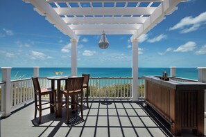 A covered outdoor area with a table and chairs, a hanging light fixture, and a view of the ocean. - Tropical Paradise: Secluded Villa With Private Beachfront (Governor's Harbour)