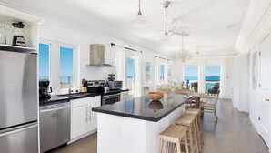 A spacious kitchen with a large island, stainless steel appliances, and a view to the outside. - Island Paradise: Secluded Retreat, Breathtaking Views (Governor's Harbour)