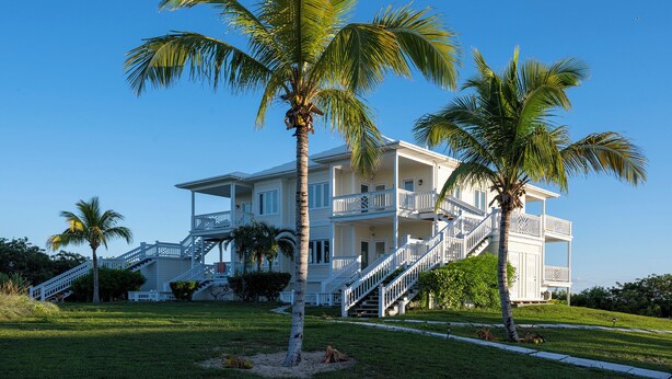 A large, two-story house with a balcony and a staircase leading to the upper floor. - Island Hideout: Quaint Cottage, Moments From The Beach (James Cistern)