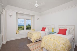 A hotel room with two beds, a ceiling fan, a window with a view, and a striped rug. - Coastal Retreat: Newly Remodeled Beach House With Pool (Governor's Harbour)