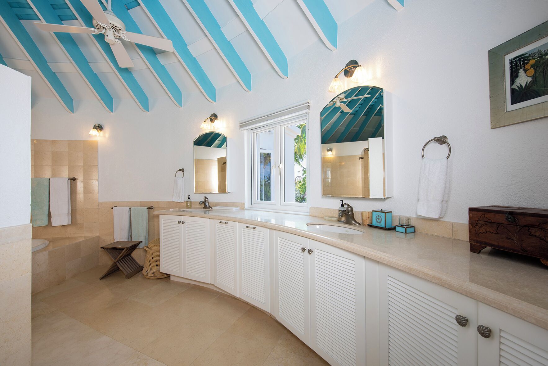 Un bagno con un ampio lavabo, due specchi, una ventola a soffitto e una finestra.