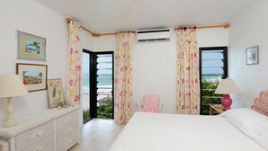 A bedroom with a bed, a dresser, a chair, and a view of the outdoors. - Oceanfront Elegance: Lovely Home With Views (Savannah Sound)