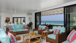 A spacious balcony with wicker furniture, a glass table, and a view of the ocean. - Oceanfront Elegance: Lovely Home With Views (Savannah Sound)