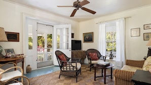 A spacious living room with wicker furniture, a ceiling fan, and a view through a glass door. - Captain'S Cove: Historic House Near Town And Beach (Governor's Harbour)
