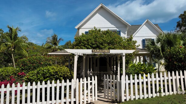 A white house with a porch labeled "Tamarind" and a white picket fence in front. - Captain'S Cove: Historic House Near Town And Beach (Governor's Harbour)