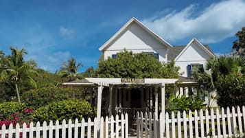 A white house with a porch labeled "Tamarind" and a white picket fence in front.